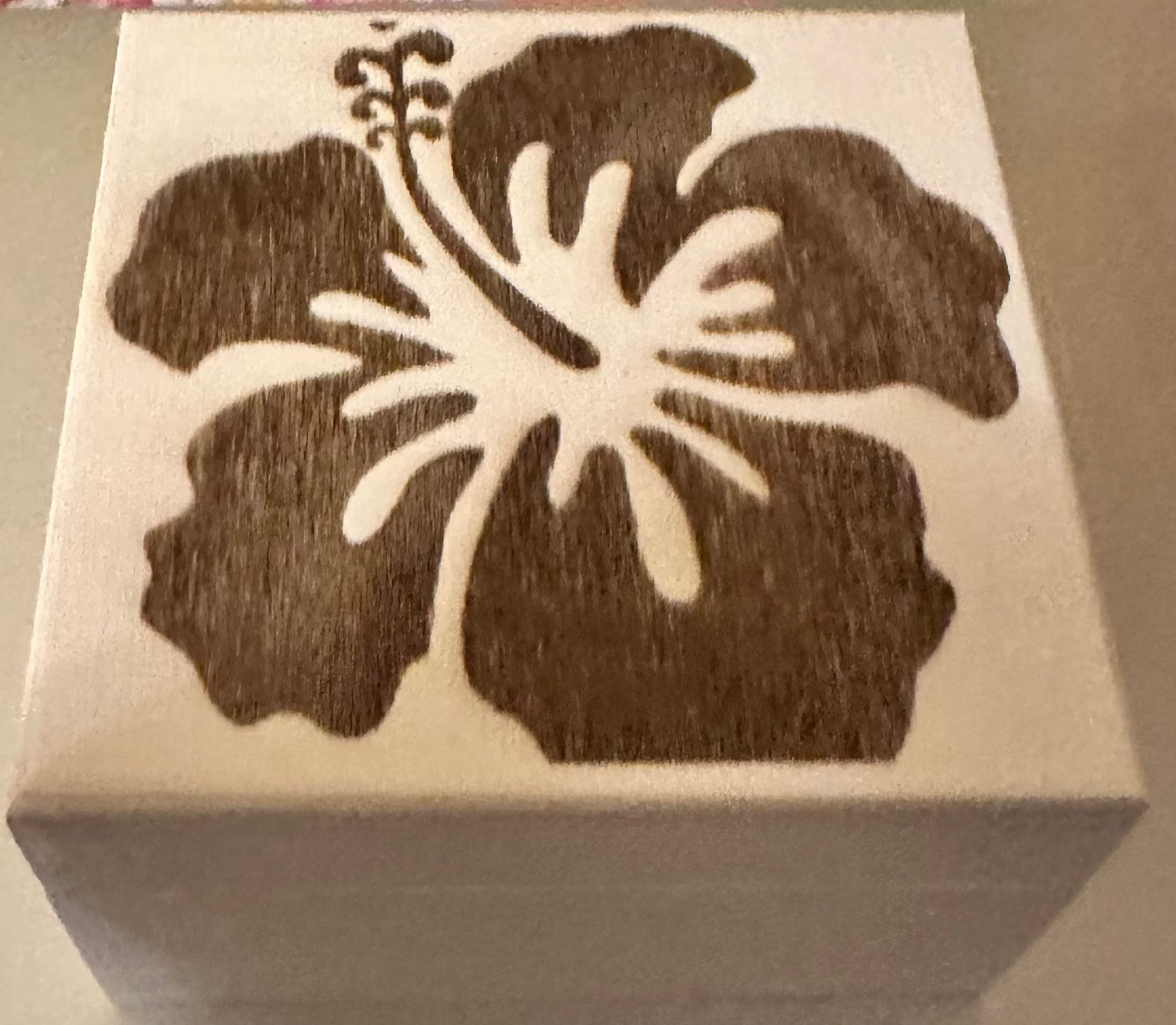 A square wooden box with a dark brown laser-burned hibiscus flower design on the lid.  Perfect for storing small pieces of jewelry or other small items.
