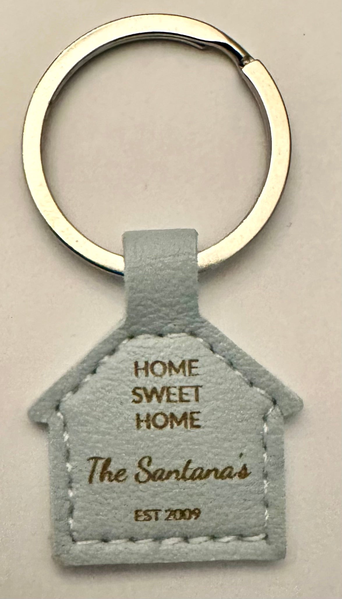 House-shaped light blue faux leather keychain laser engraved with Home Sweet Home The Santanas Est 2009